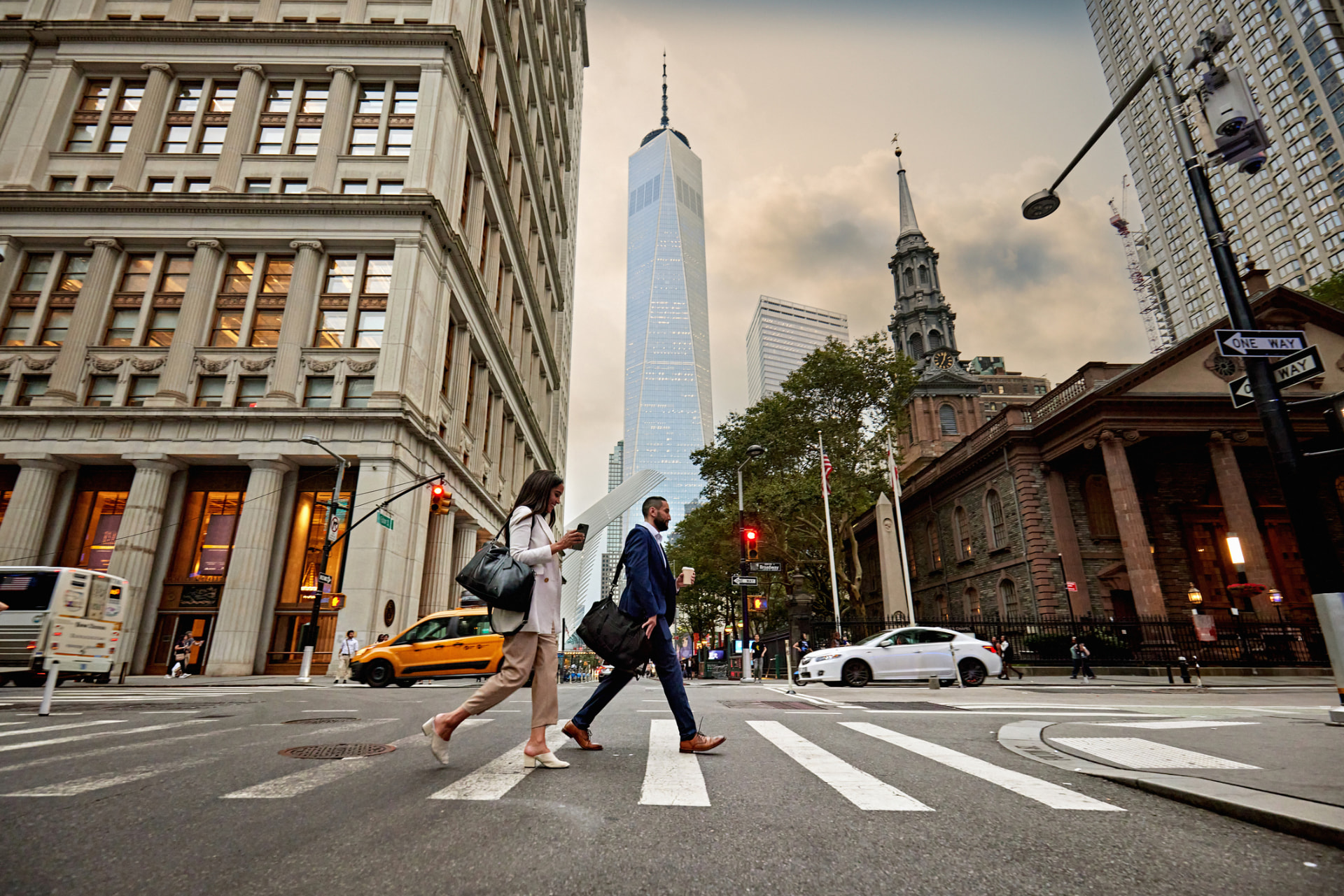 Two business professionals crossing a downtown street at dusk
